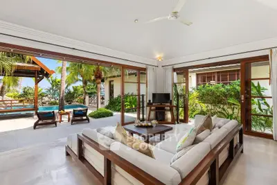 Luxurious open-plan living room with tropical garden view and elegant wooden furniture.