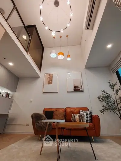 Modern living room with high ceiling, stylish lighting, and cozy seating area.