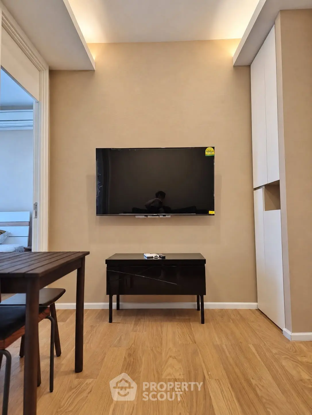 Modern living room with wall-mounted TV and sleek furniture in a cozy apartment setting.