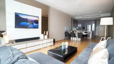 Modern living room with open kitchen, sleek furniture, and wall-mounted TV in stylish apartment.