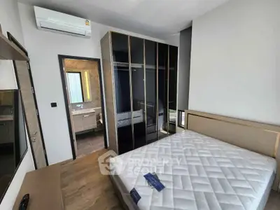 Modern bedroom with sleek wardrobe and ensuite bathroom in stylish apartment.
