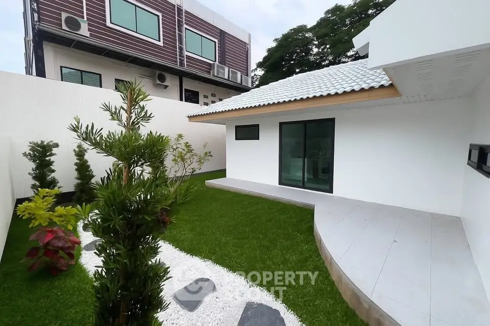 Modern minimalist house with lush garden and sleek exterior design.