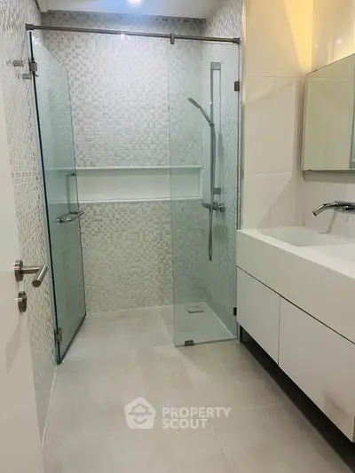Modern bathroom with glass shower and sleek vanity in contemporary design.
