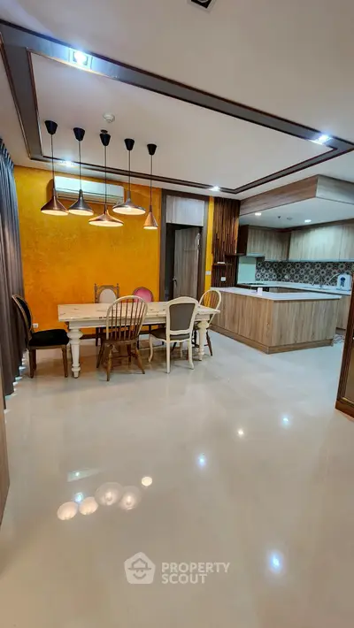 Spacious modern kitchen and dining area with elegant lighting and open layout.