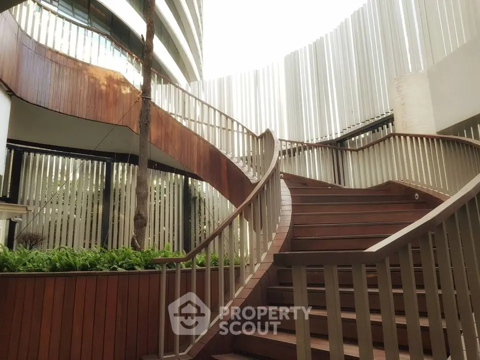 Elegant modern building entrance with stylish wooden staircase and lush greenery