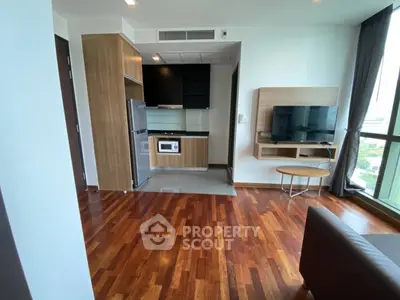 Modern living room with open kitchen and wooden flooring in high-rise apartment.