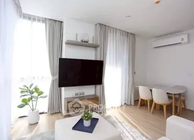 Bright modern living room with large TV and dining area, featuring elegant curtains and wooden flooring.