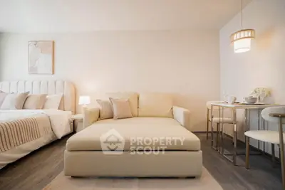 Modern studio apartment with cozy bed, stylish sofa, and elegant dining area.