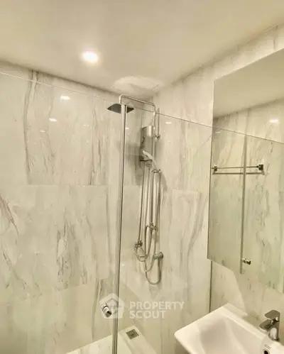 Modern bathroom with marble walls and glass shower enclosure