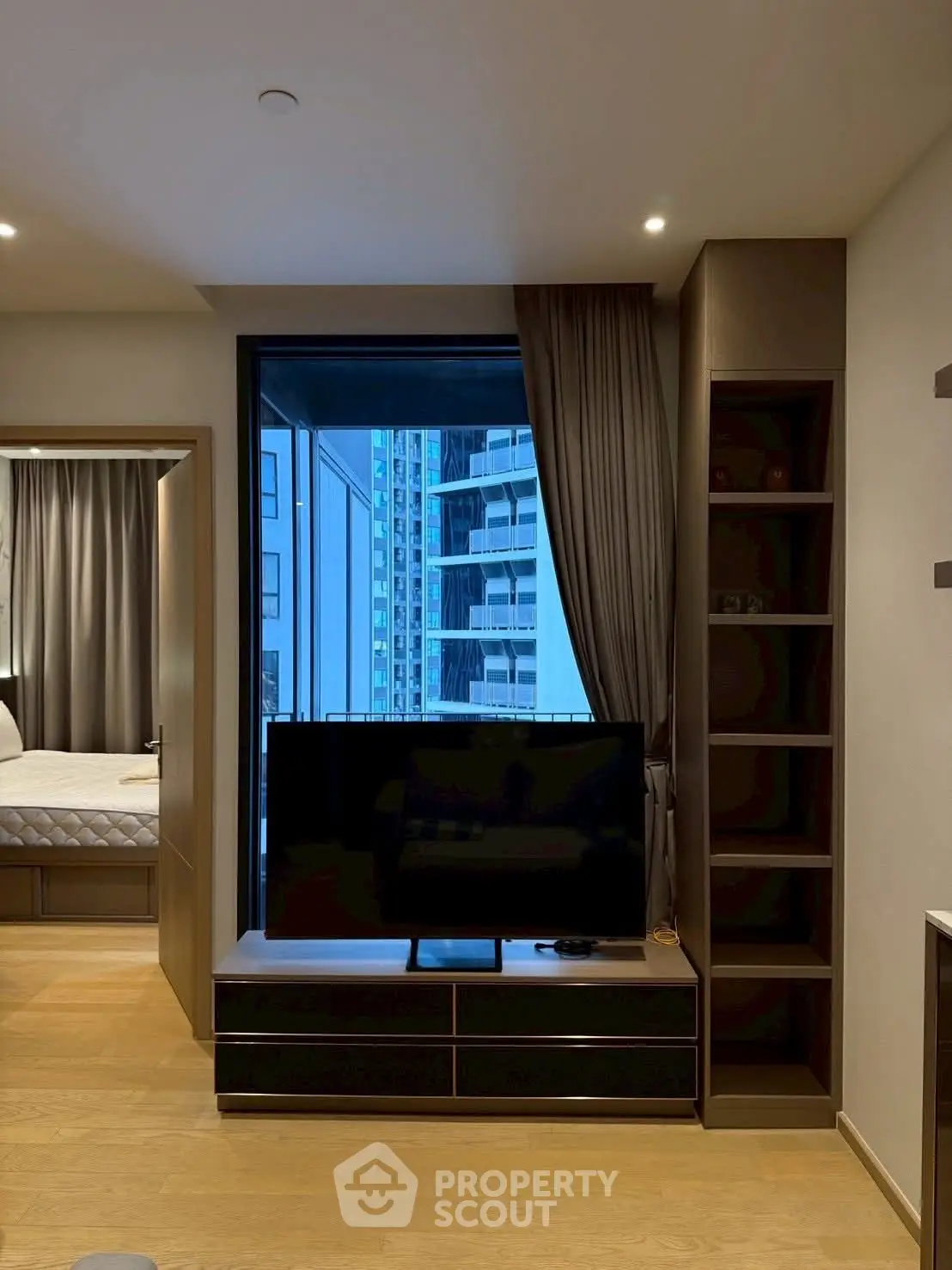 Modern living room with TV and city view, featuring sleek design and cozy ambiance.