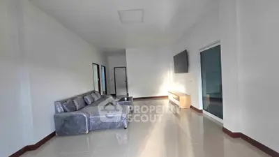 Spacious modern living room with sleek tile flooring and stylish gray sofa, perfect for relaxation.