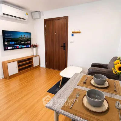Modern living room with wooden flooring, wall-mounted TV, and stylish dining setup.
