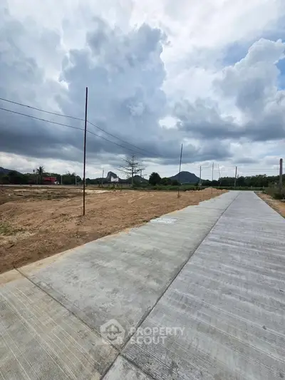 Expansive plot of land with paved road and scenic mountain views, perfect for development opportunities.