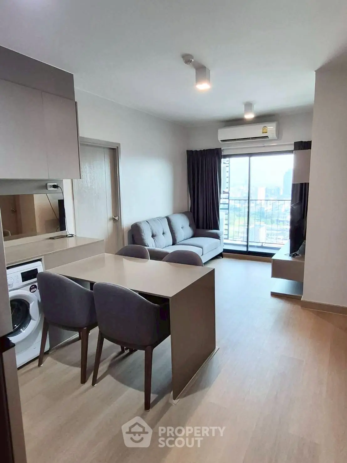 Modern living room with open kitchen and city view balcony in high-rise apartment.