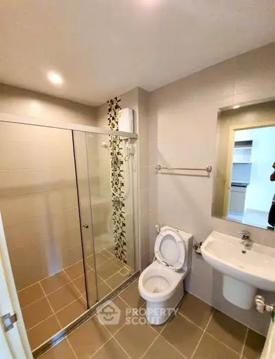 Modern bathroom with glass shower enclosure and sleek fixtures in a contemporary apartment.