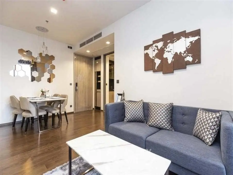 Modern living room with stylish decor and dining area, featuring a cozy sofa and elegant wall art.