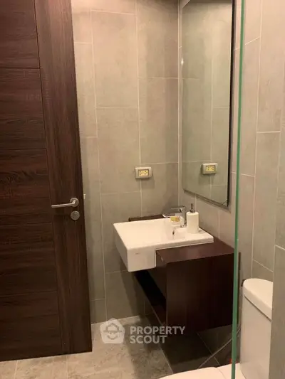 Modern bathroom with sleek sink and wooden accents in a contemporary apartment.