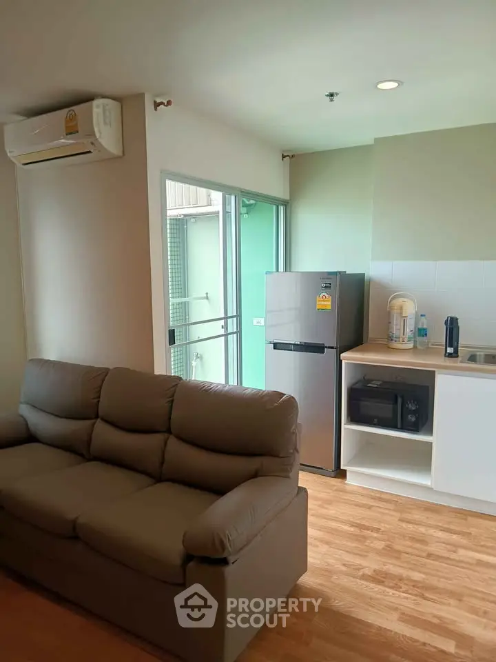 Modern living room with cozy sofa and sleek kitchen area in a bright apartment.