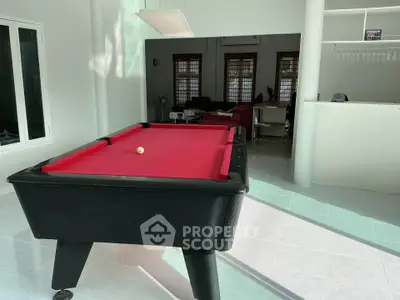 Spacious living area with red pool table and modern decor