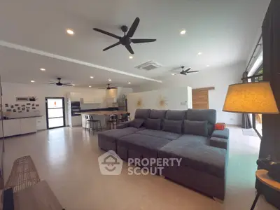 Spacious modern living room with large sectional sofa and open kitchen layout.