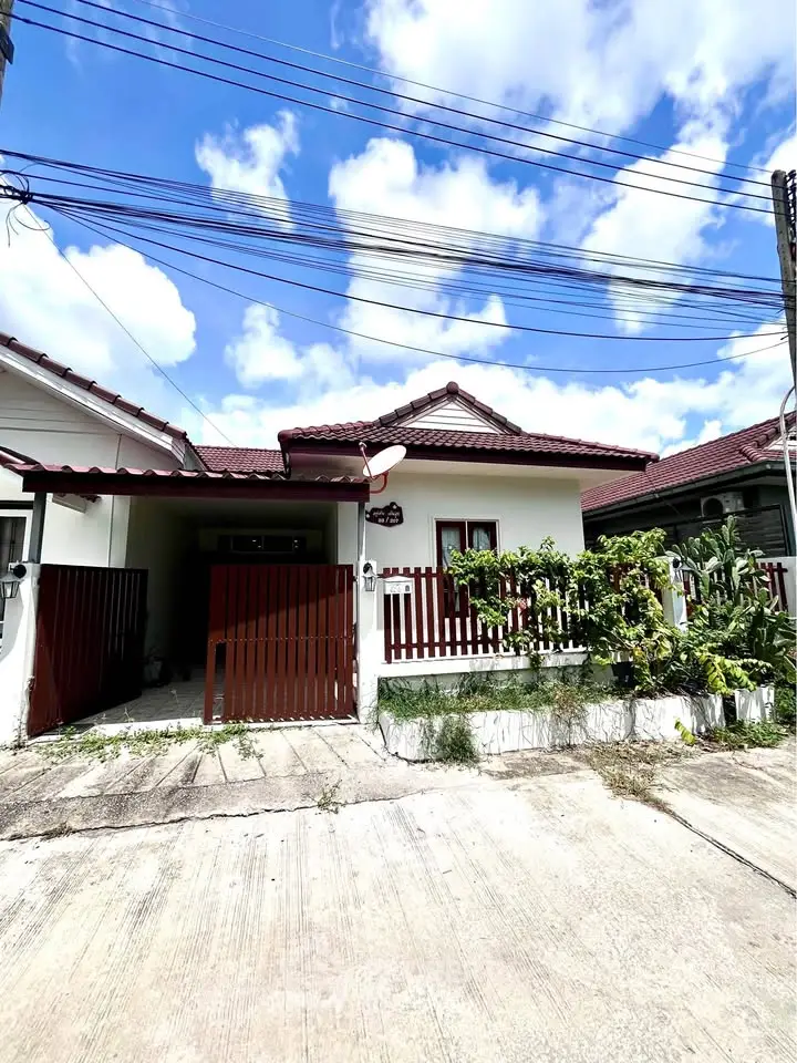 Charming single-story house with red roof and fenced garden in a serene neighborhood.