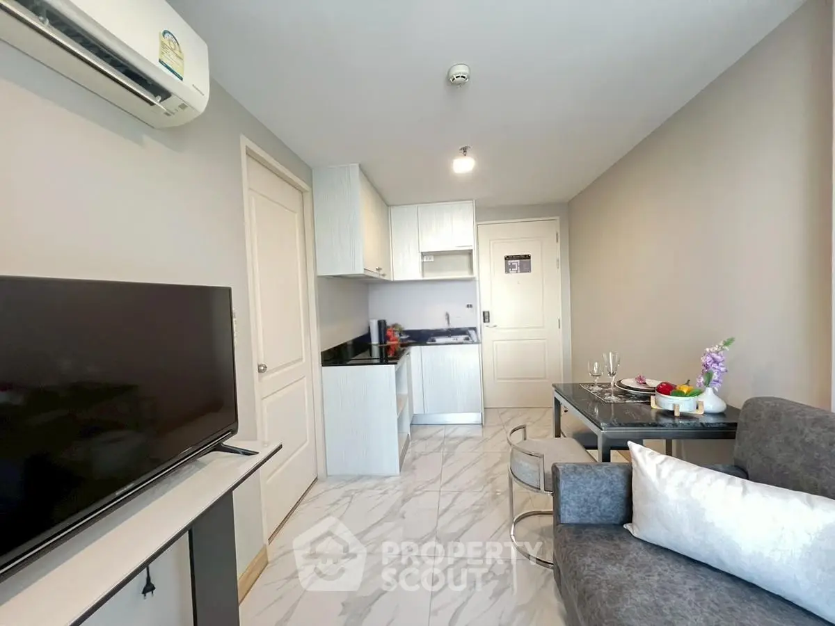 Modern apartment interior with open kitchen and cozy living area, featuring sleek furniture and stylish decor.