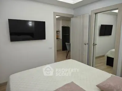Modern bedroom with wall-mounted TV and mirrored closet doors, showcasing sleek interior design.