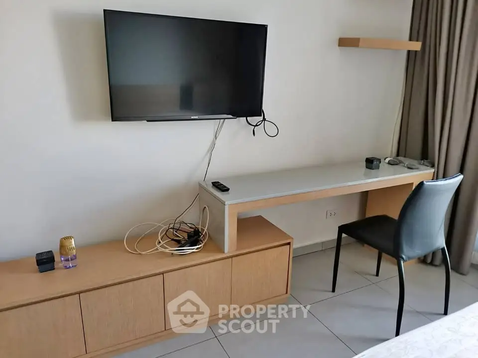 Modern study area with wall-mounted TV and sleek desk in a stylish apartment.