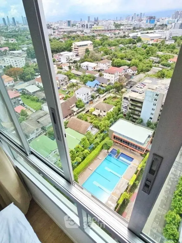 Stunning high-rise view of cityscape and pool from modern apartment window.