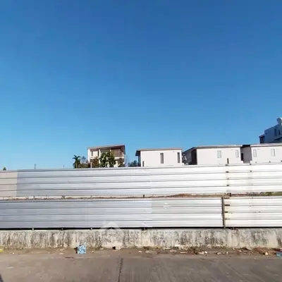 Modern residential buildings behind a metal fence under a clear blue sky.