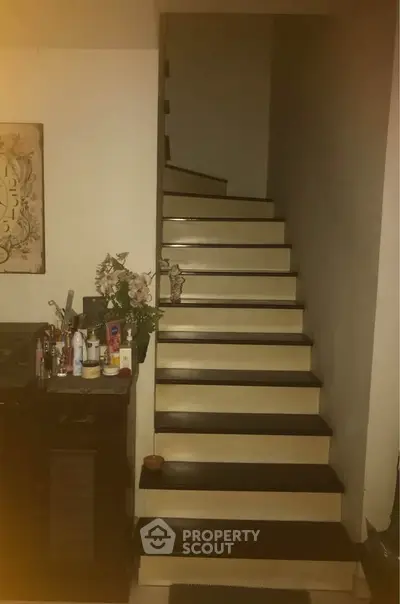 Cozy interior staircase with decorative side table and floral arrangement.