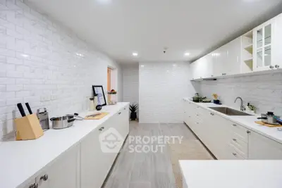 Spacious modern kitchen with sleek white cabinetry and elegant tile backsplash.