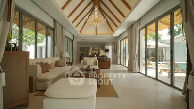 Luxurious living room with high ceilings, elegant chandelier, and large windows overlooking a pool area.