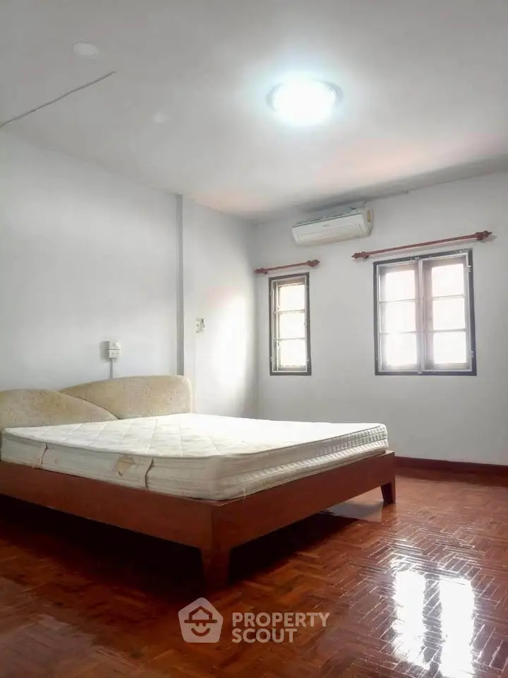 Spacious bedroom with wooden flooring and natural light