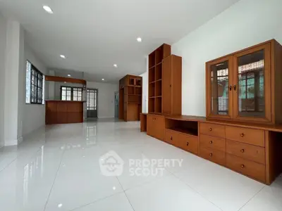 Spacious open-plan living area with built-in wooden cabinets and glossy tiled flooring