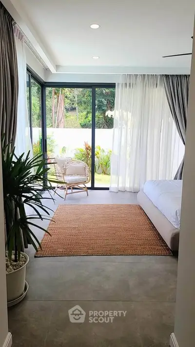 Spacious bedroom with large windows and garden view, featuring elegant decor and natural light.