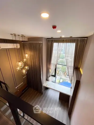 Stunning loft-style living room with high ceilings and large window offering a panoramic city view.