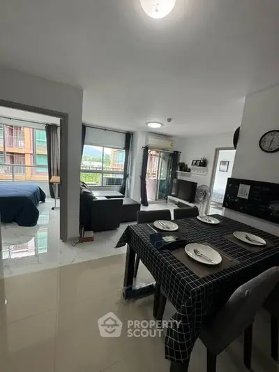 Modern open-plan apartment with dining area, living room, and bedroom, featuring stylish decor and natural light.