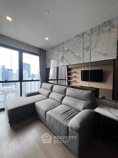 Modern living room with city view, featuring a plush gray sofa and marble accents, perfect for urban living.