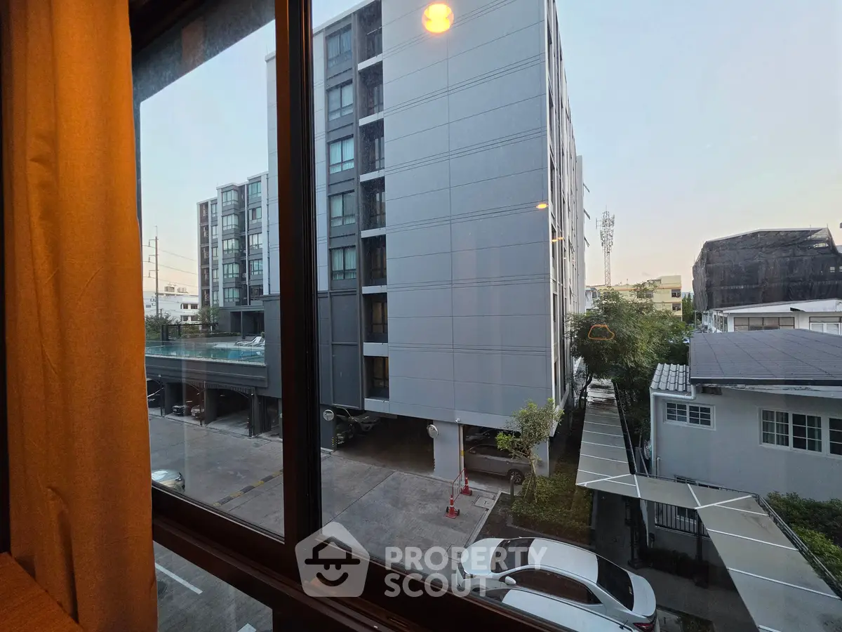 Modern apartment view from window showcasing urban landscape and parking area.