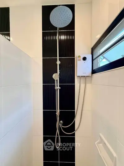 Modern bathroom shower with sleek black and white tiles and a rain showerhead.