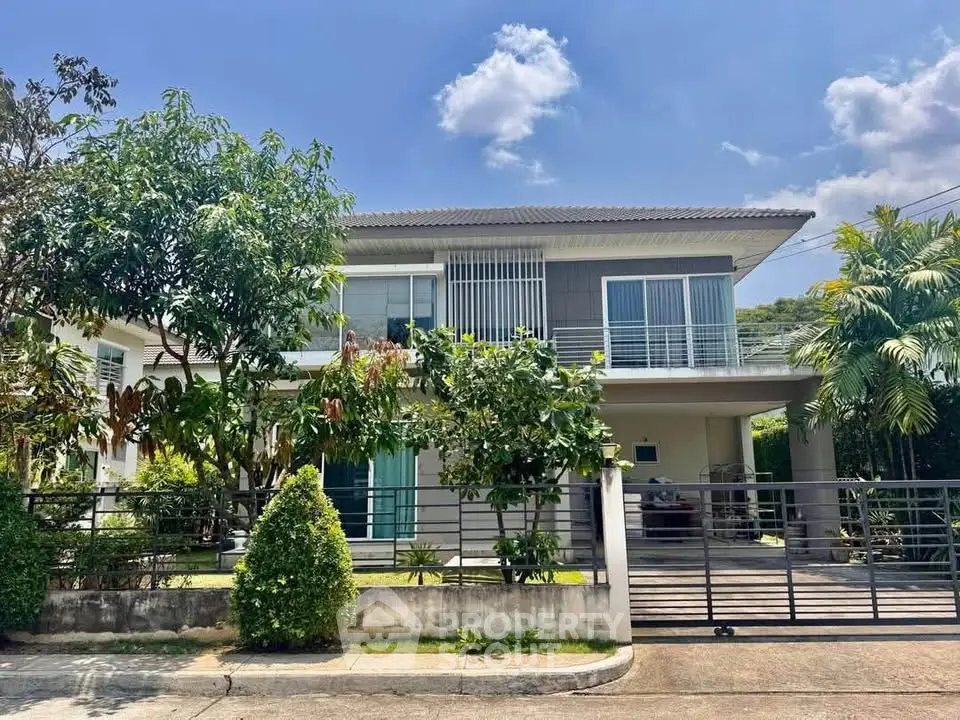 Modern two-story house with lush garden and spacious driveway under clear blue sky.