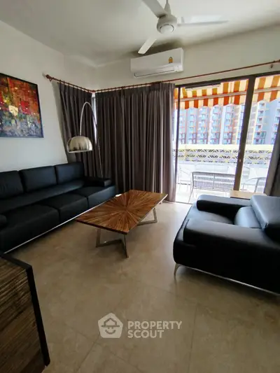 Modern living room with sleek black sofas, stylish coffee table, and balcony view in a high-rise apartment.