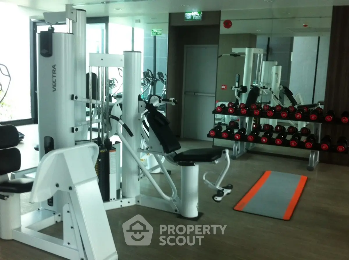 Modern gym with state-of-the-art equipment and mirrored walls in luxury apartment building.