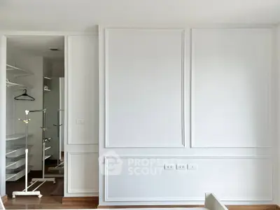 Spacious white-walled room with elegant paneling and built-in closet, perfect for modern living.