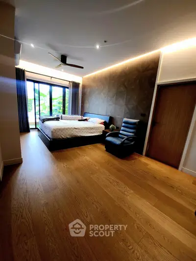 Spacious bedroom with modern design and large windows overlooking greenery.