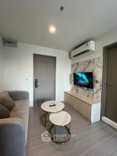 Modern living room with sleek design, featuring a comfortable sofa, stylish coffee tables, and a wall-mounted TV.