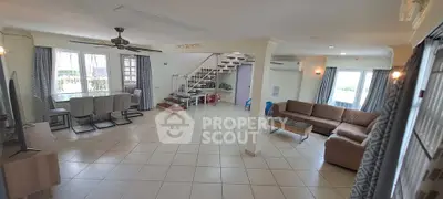 Spacious open-plan living room with modern furniture and staircase, ideal for family gatherings.