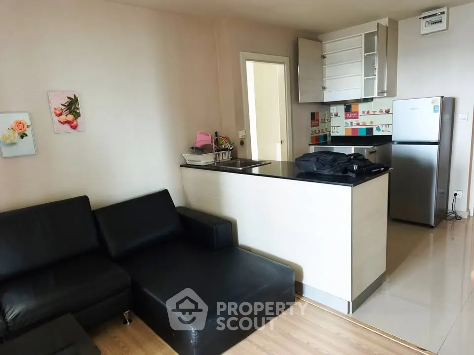 Modern open-layout kitchen and living room with sleek black furniture and stainless steel appliances.