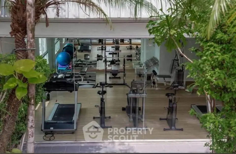 Modern gym with state-of-the-art equipment and lush greenery view, perfect for fitness enthusiasts.